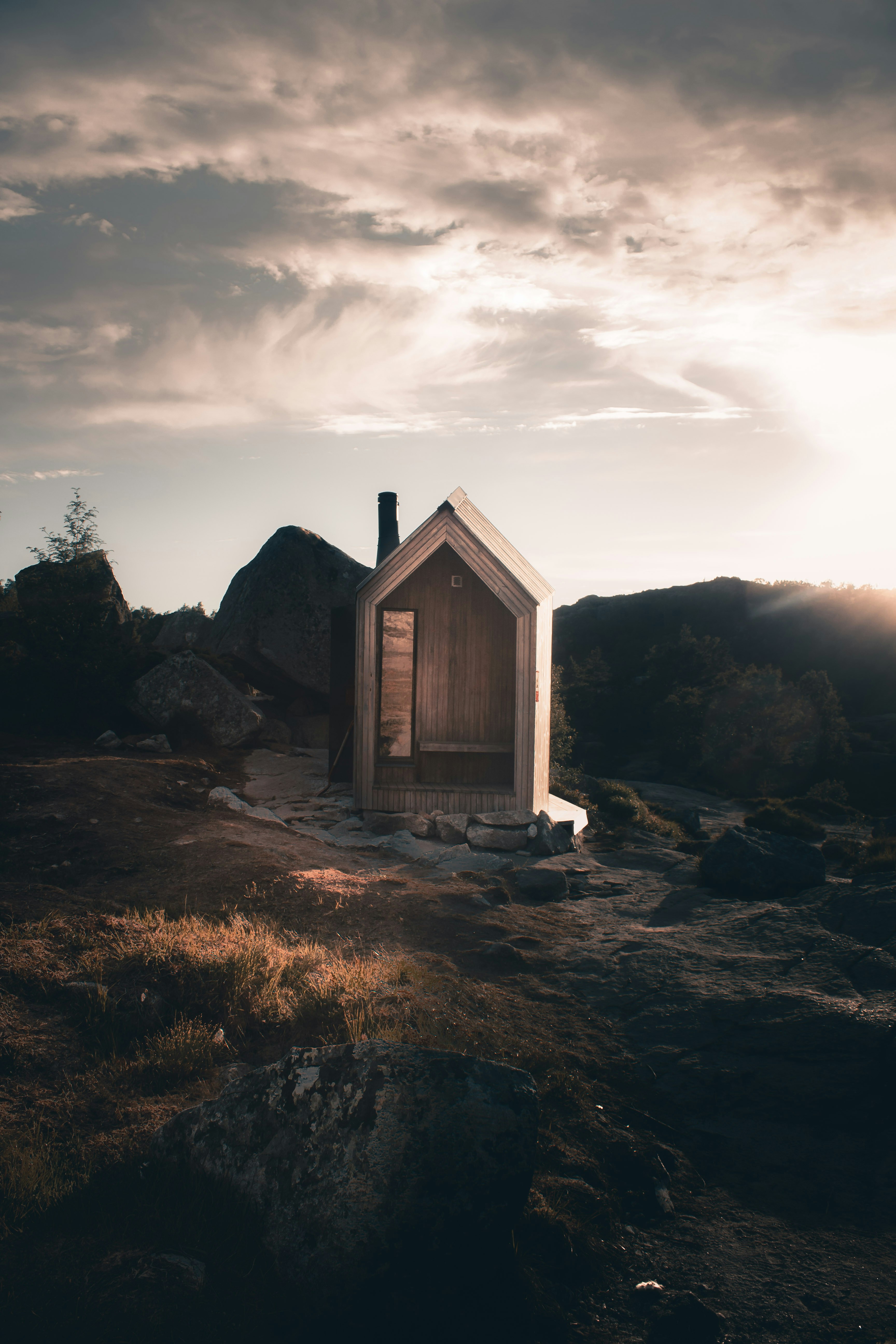 Norwegian sauna cabin on rocky mountain at sunset